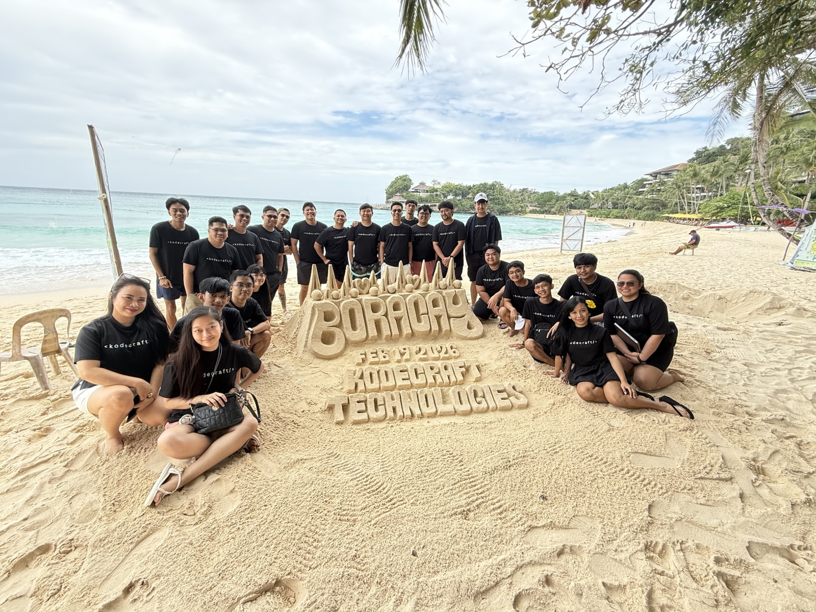 The team gathered on the beach around a Boracay sand sculpture