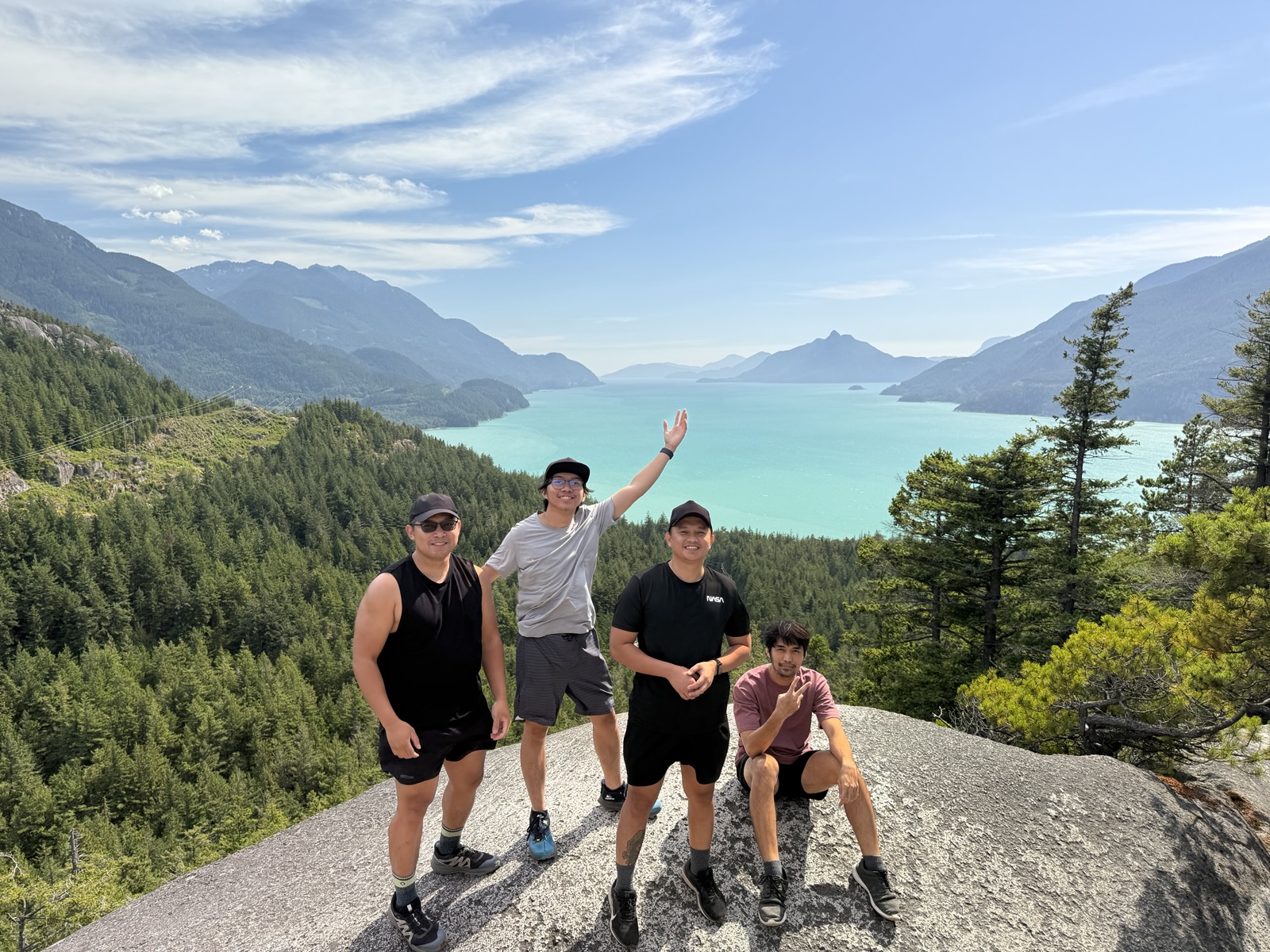 Four teammates at a rocky viewpoint above turquoise water in Canada