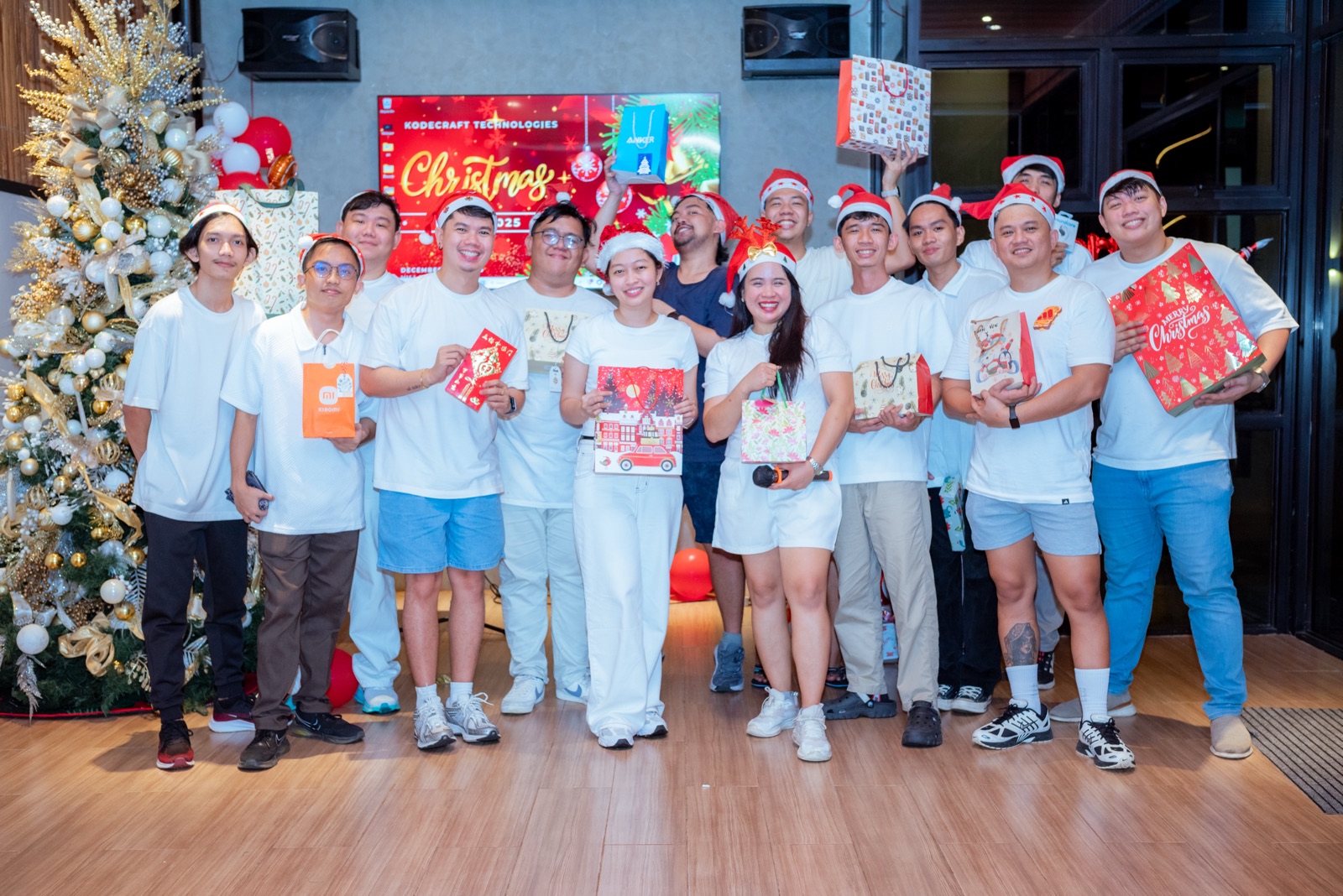 The team holding gifts beside a Christmas tree