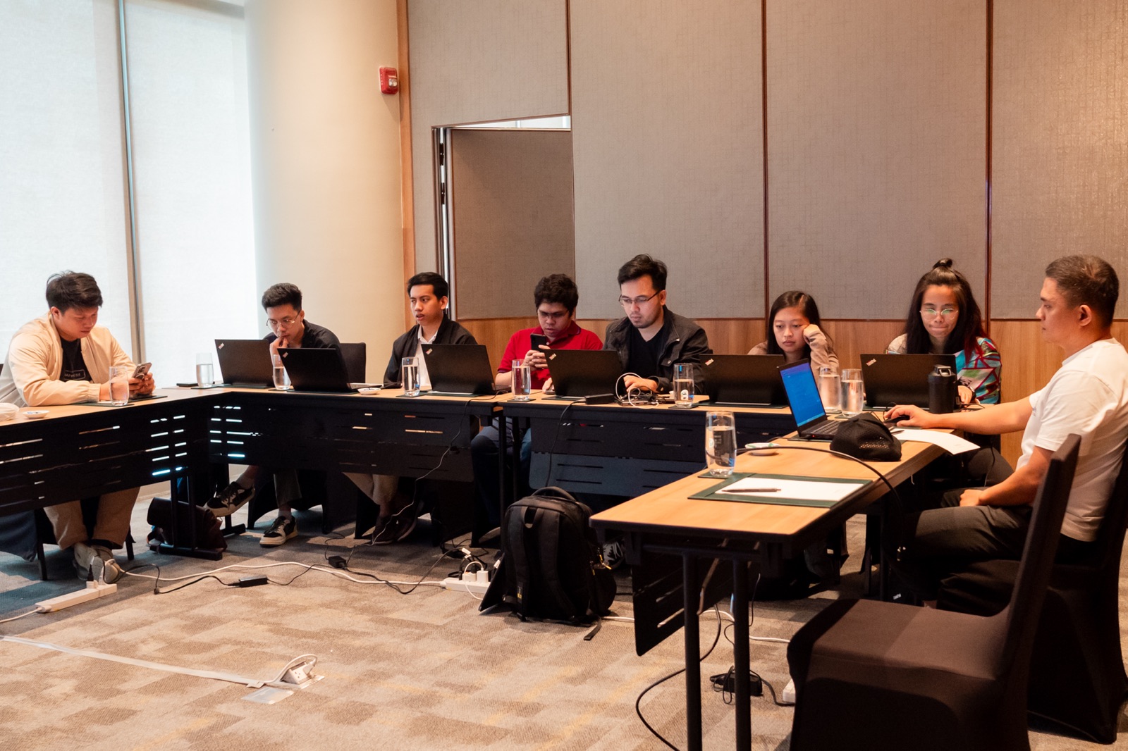 Teammates discussing their work around U-shaped tables with laptops