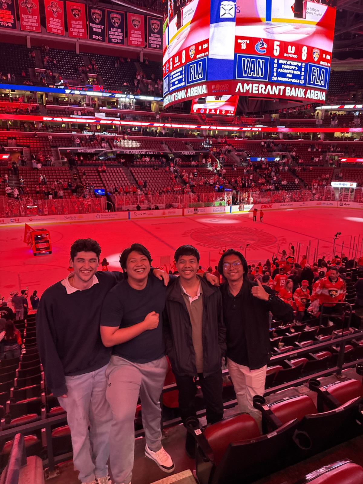 Four teammates in the stands beside the ice at a hockey game