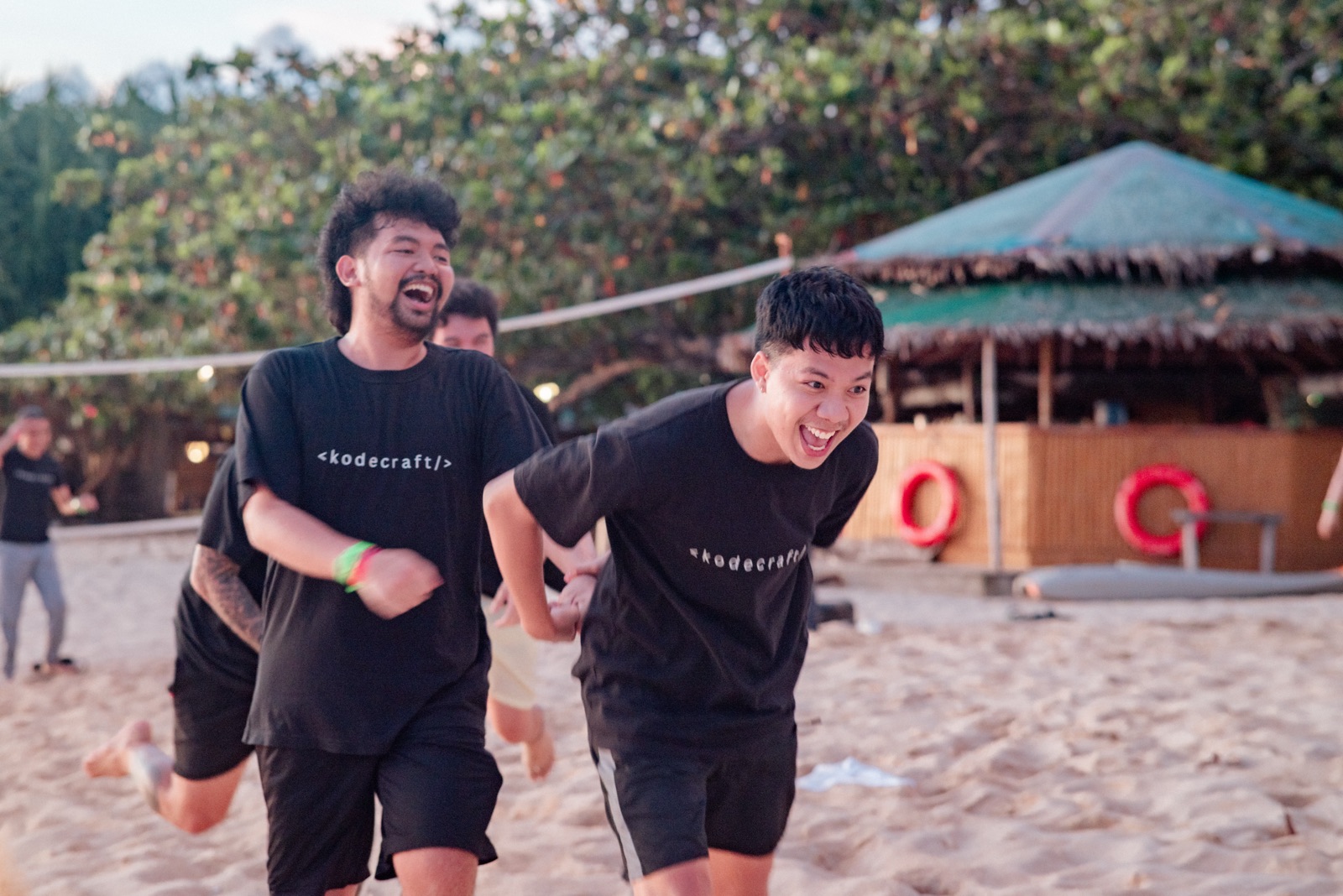 Two teammates laughing while running during a beach activity